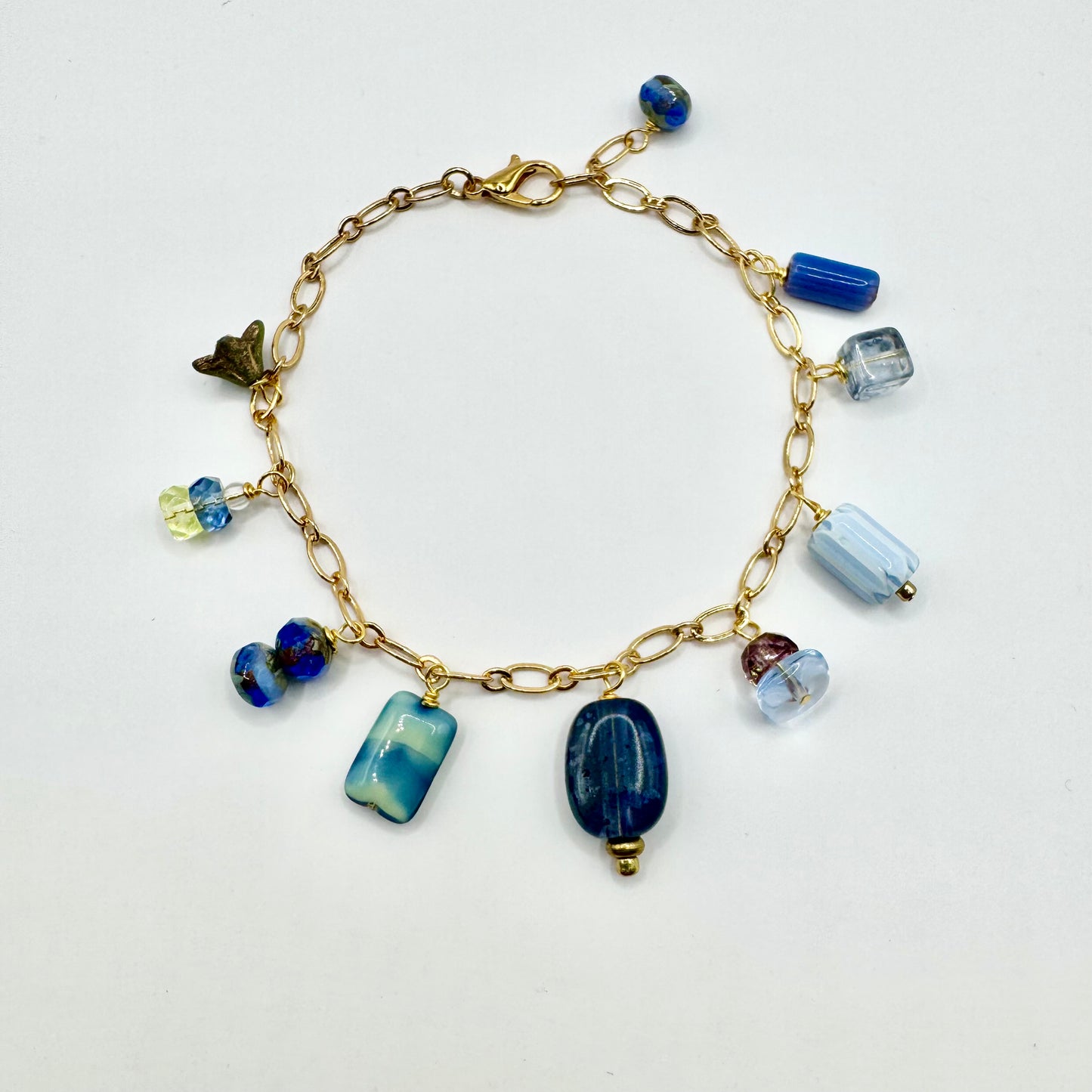 Gold bracelet with blue and clear beads on a white background
