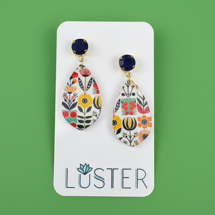 Pair of floral teardrop earrings on a Luster branded card against a textured green background.