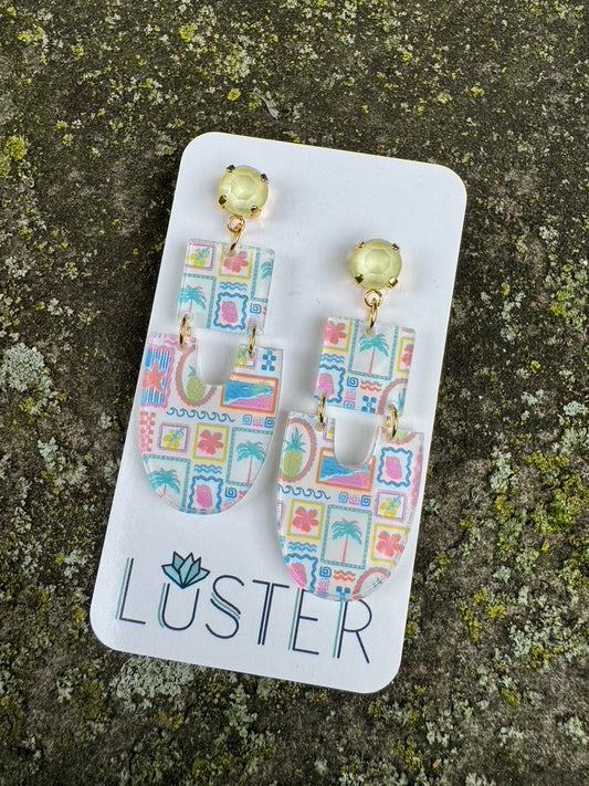 Pair of earrings on a Luster branded card against a textured stone background