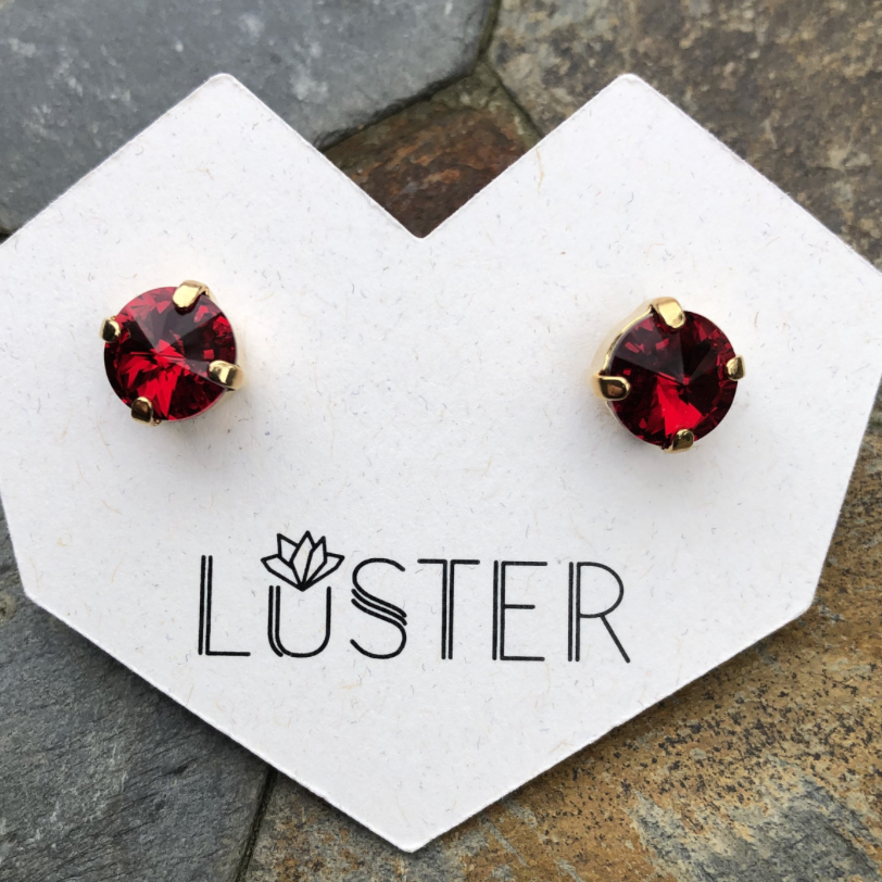 Red gemstone stud earrings on a Luster branded card.