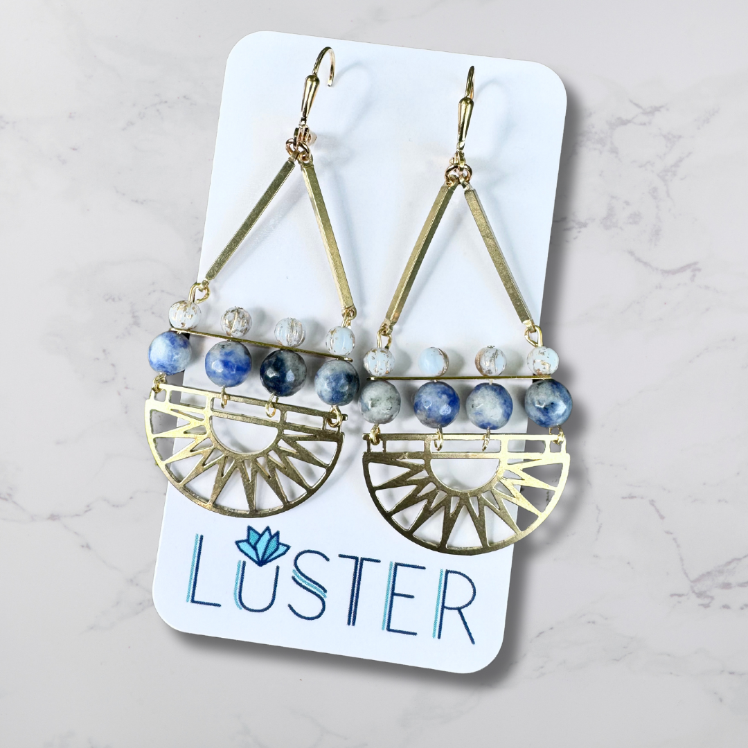 Art deco style statement earrings with brass fans, and blue stone and glass on a white Luster branded card.