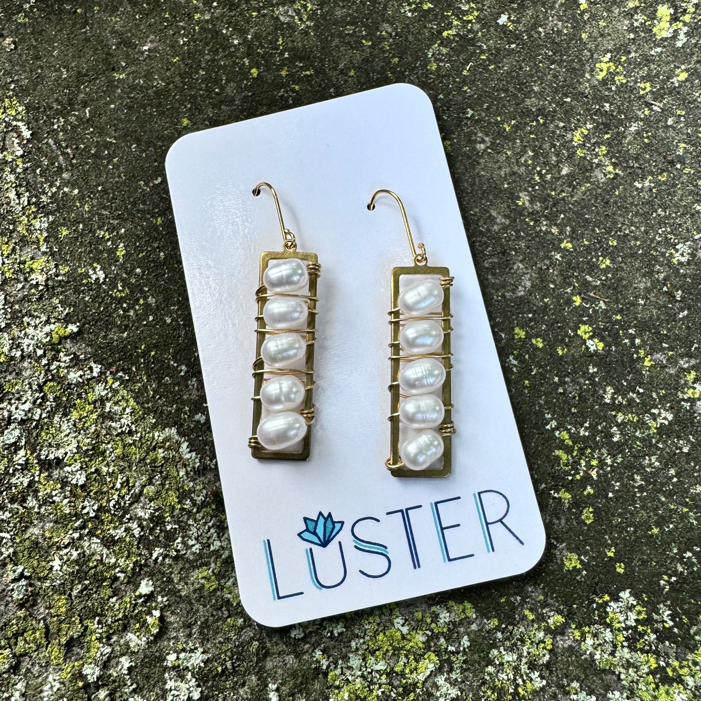 A pair of handwrapped pearl drop earrings displayed on a white card with the brand name 'LUSTER' written at the bottom.