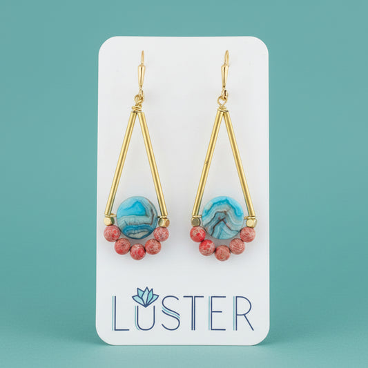 Gold earrings with blue and red beads on a Luster branded card.