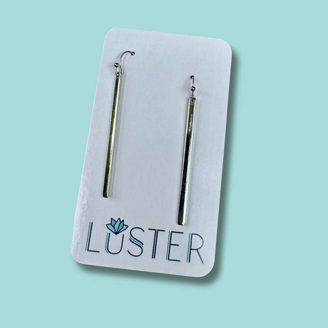 Silver stick earrings on a Luster branded card against a light blue background
