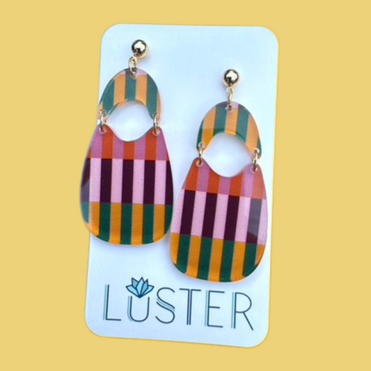 Colorful striped earrings on a Luster branded card against a yellow background