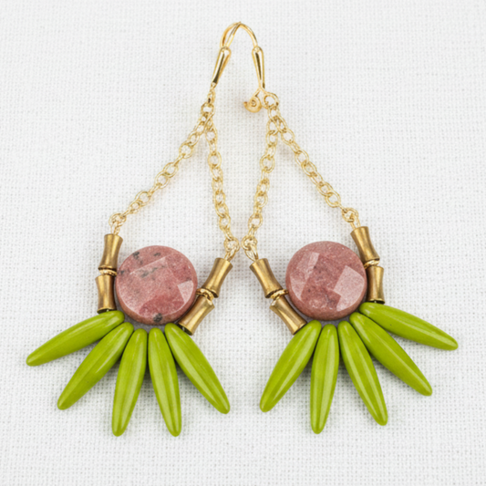 Earrings with green spikes and pink stones on a white linen background