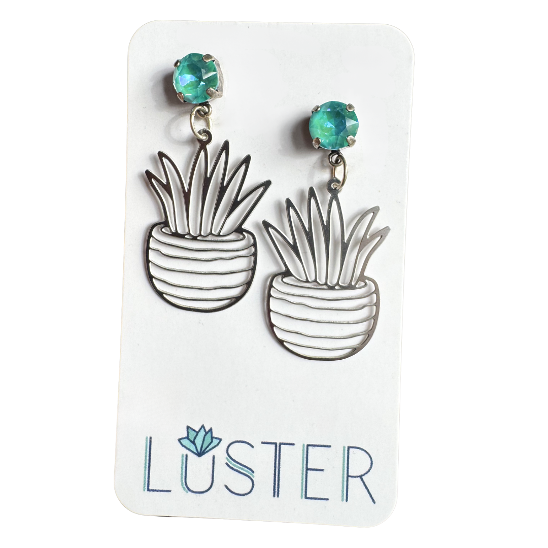 Plant-shaped earrings with green crystals on a Luster branded card.
