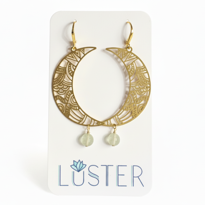 Gold crescent moon earrings with dangling beads on a Luster branded card.