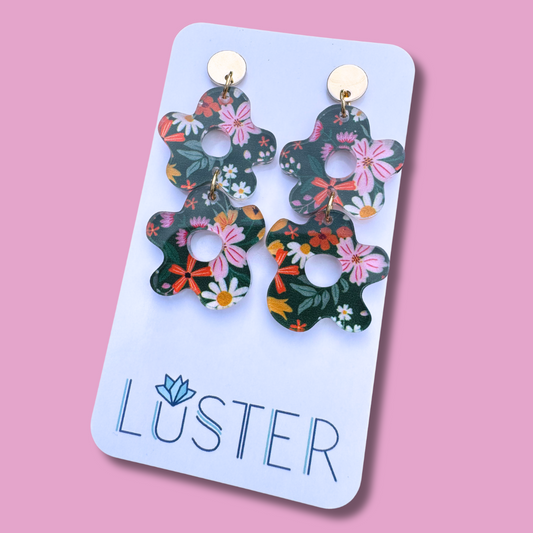 Floral earrings on a Luster branded card against a pink background
