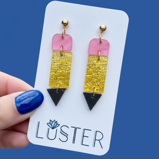 Pencil earrings on a Luster branded card held by a hand with blue nail polish.