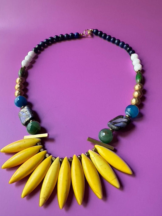 Necklace with yellow leaf-like pendants and multicolored beads on a purple background