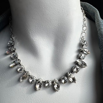 A necklace with clear Swarovski crystals on a mannequin wearing a denim shirt.