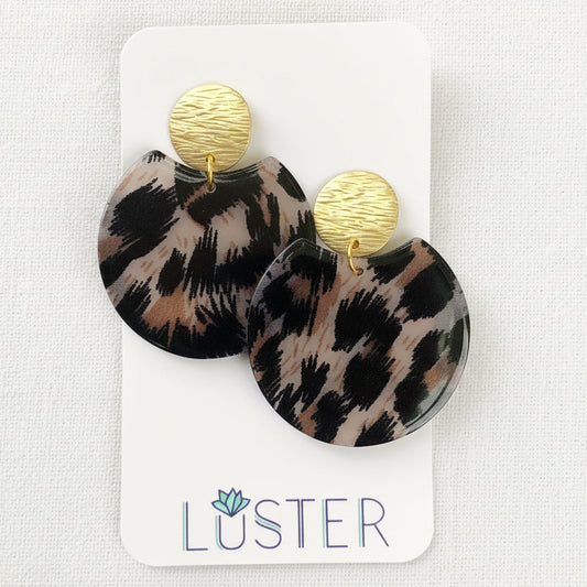 Leopard print earrings with gold accents on a Luster branded card.