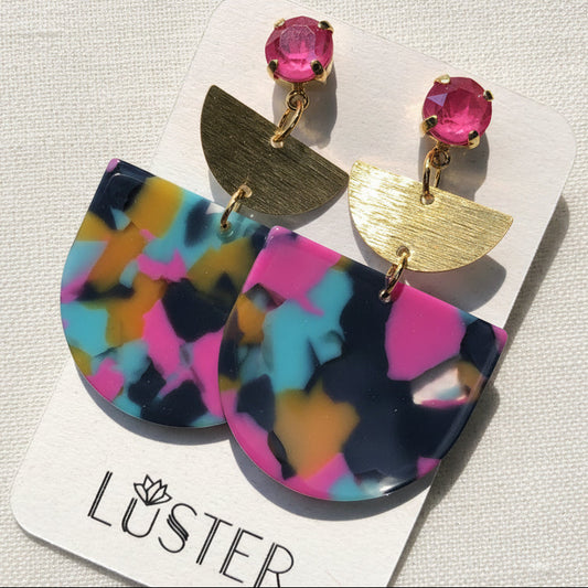 Colorful earrings with gold accents on a Luster branded card.