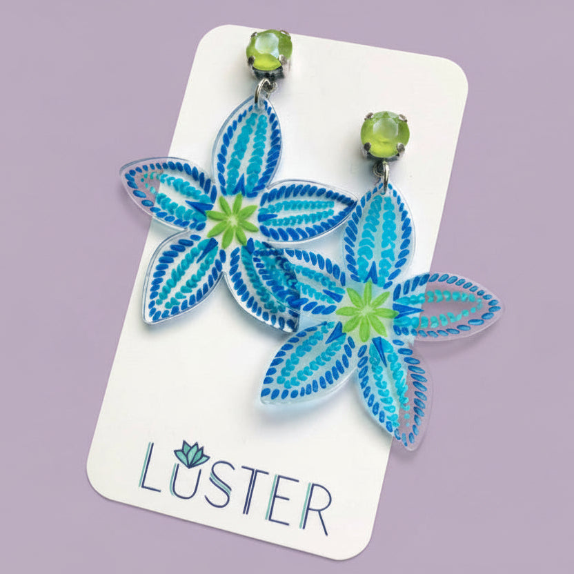 Floral earrings on a Luster branded card against a pale purple background