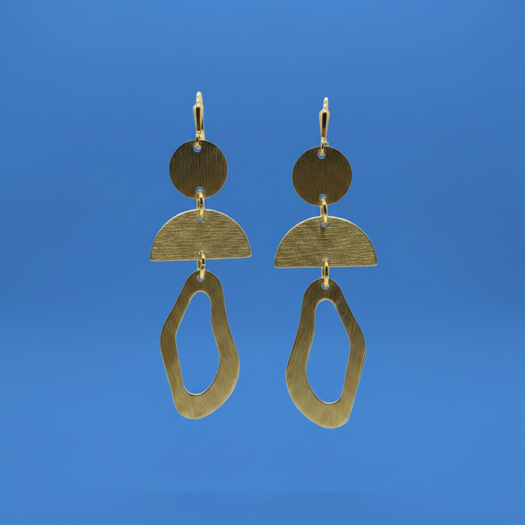 A pair of abstract geometric drop earrings made of brushed gold-toned metal, featuring stacked circular and semi-circular shapes with an irregular dangling loop, shown against a solid blue background.