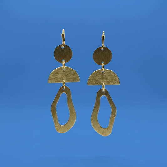 A pair of abstract geometric drop earrings made of brushed gold-toned metal, featuring stacked circular and semi-circular shapes with an irregular dangling loop, shown against a solid blue background.