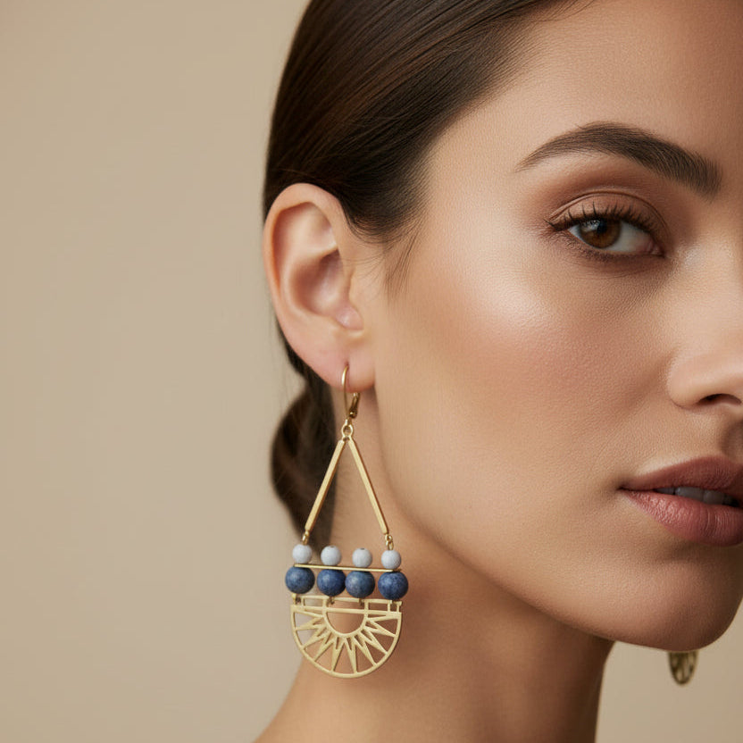 Art deco style statement earrings with brass fans, and blue stone and glass on a model