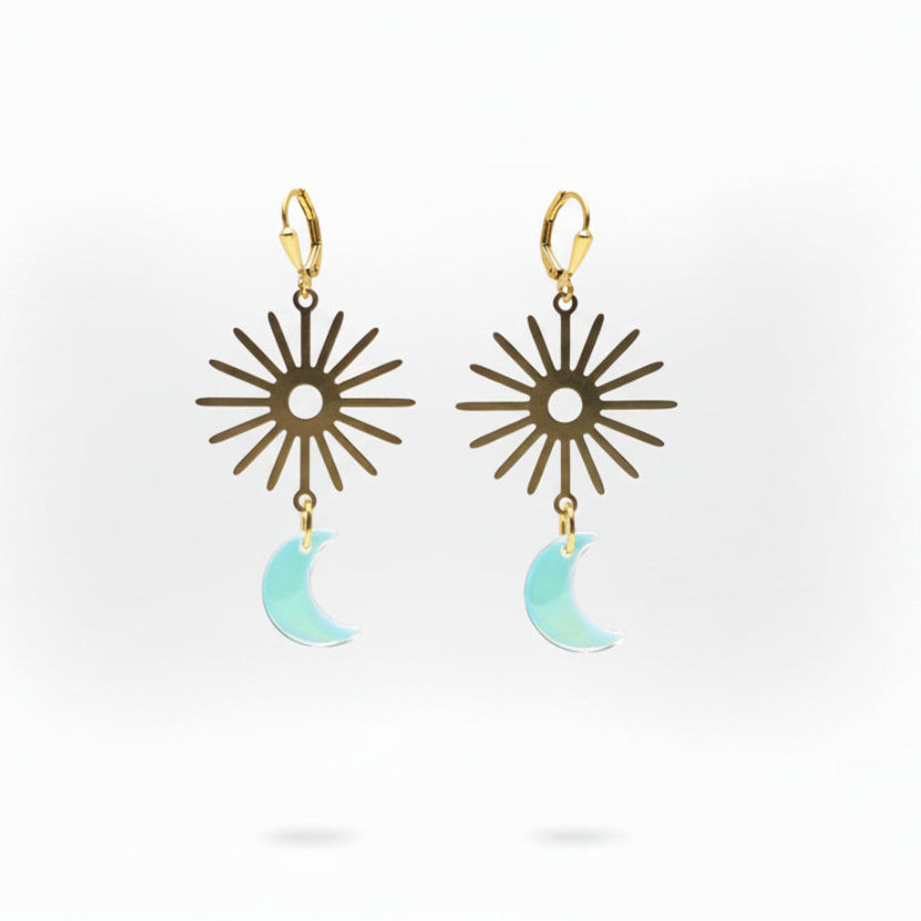 Pair of earrings with star-like design and moon-shaped pendant on a white background