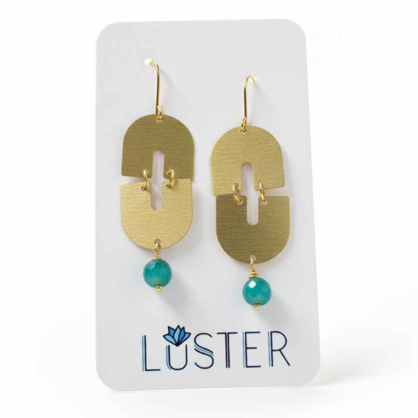 Gold earrings with green beads on a Luster branded card