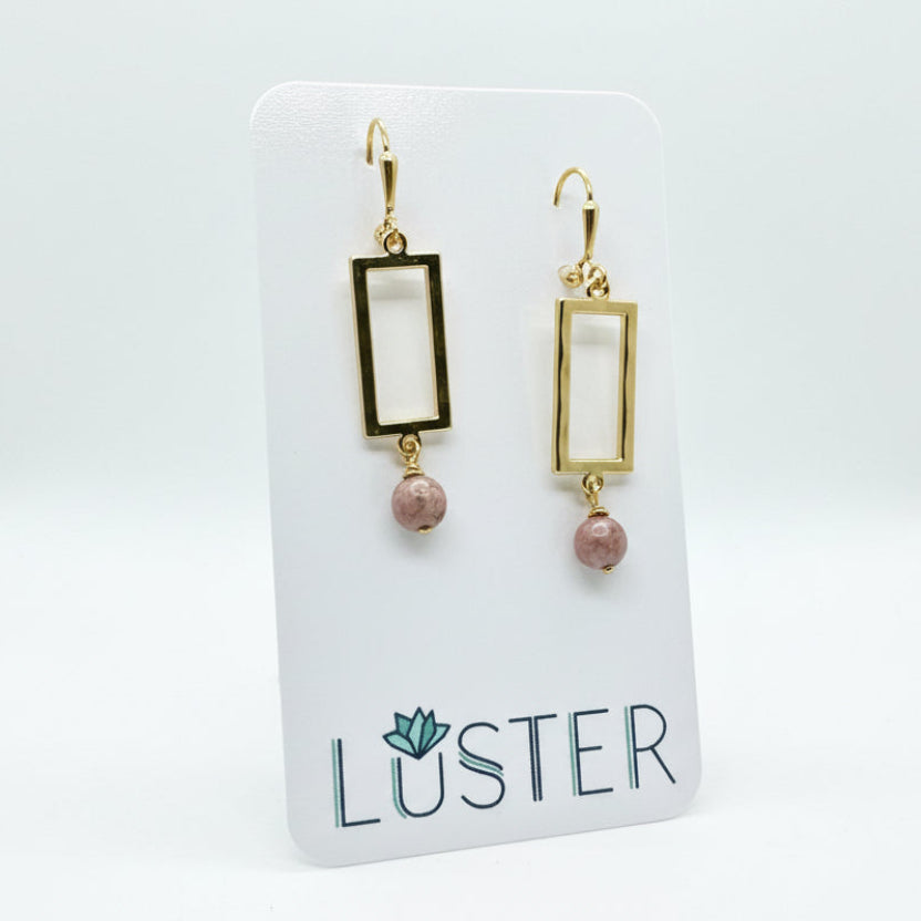 Brass and stone earrings on a branded card.