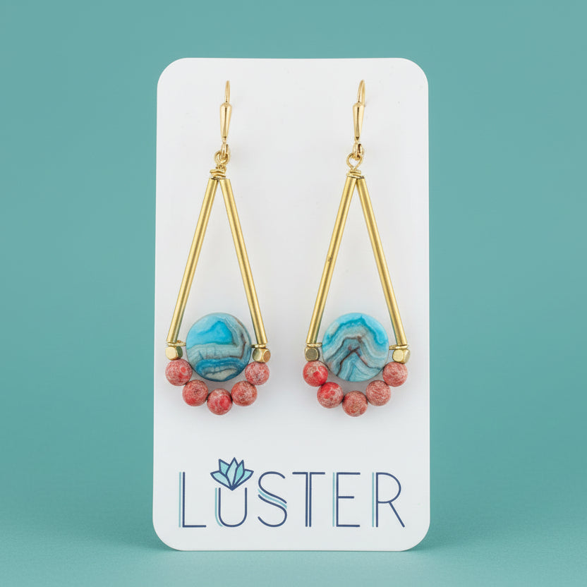 Gold earrings with blue and red beads on a Luster branded card.