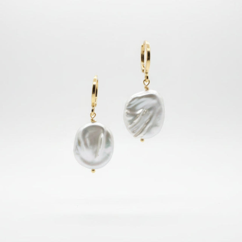 Pair of pearl earrings on a Luster branded card against a white background