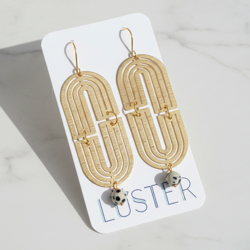 Gold arch-shaped earrings on a Luster branded card
