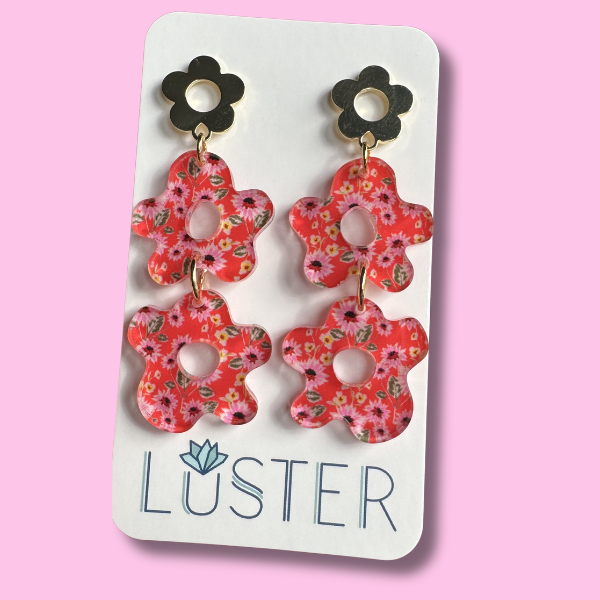 Floral earrings on a Luster branded card against a pink background