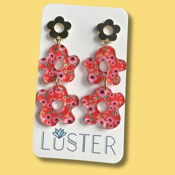 Floral earrings on a Luster branded card against a yellow background