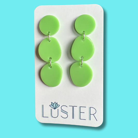 Green circular earrings on a Luster branded card against a blue background