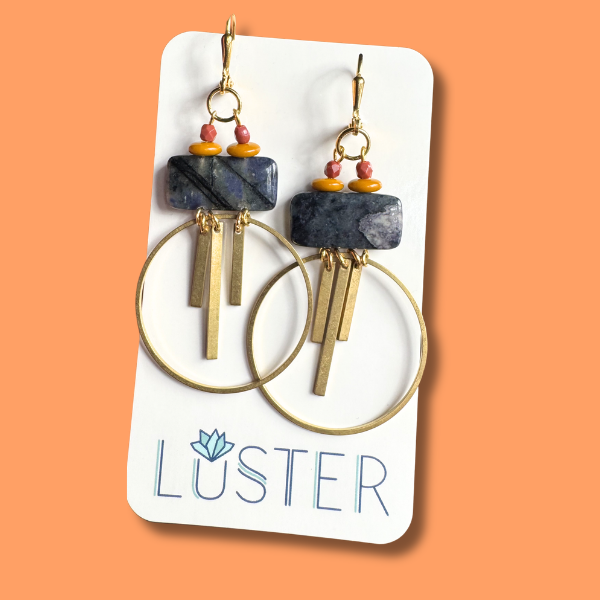 Pair of brass and stone hoop earrings on a Luster branded card against an orange background