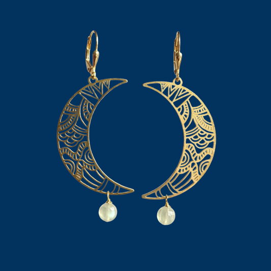 Brass celestial crescent moon cutouts with stone dangles on dark blue background