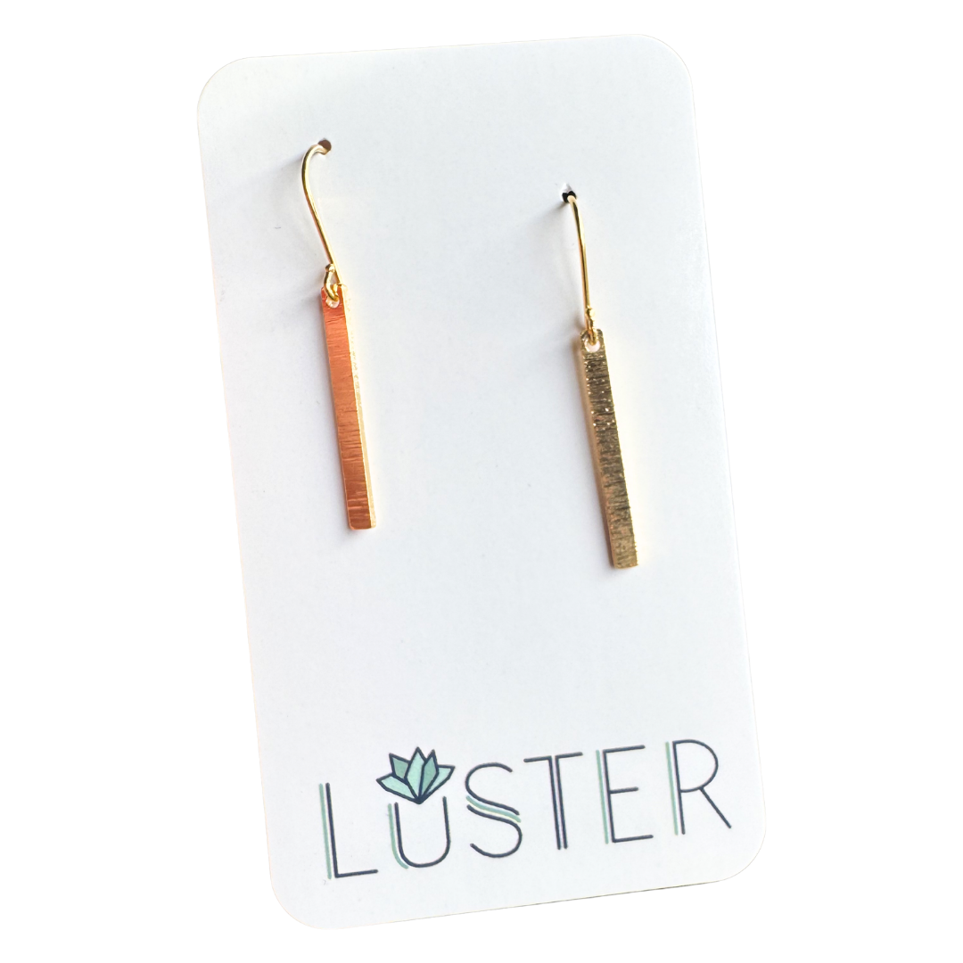 Pair of gold bar earrings on a Luster branded card.