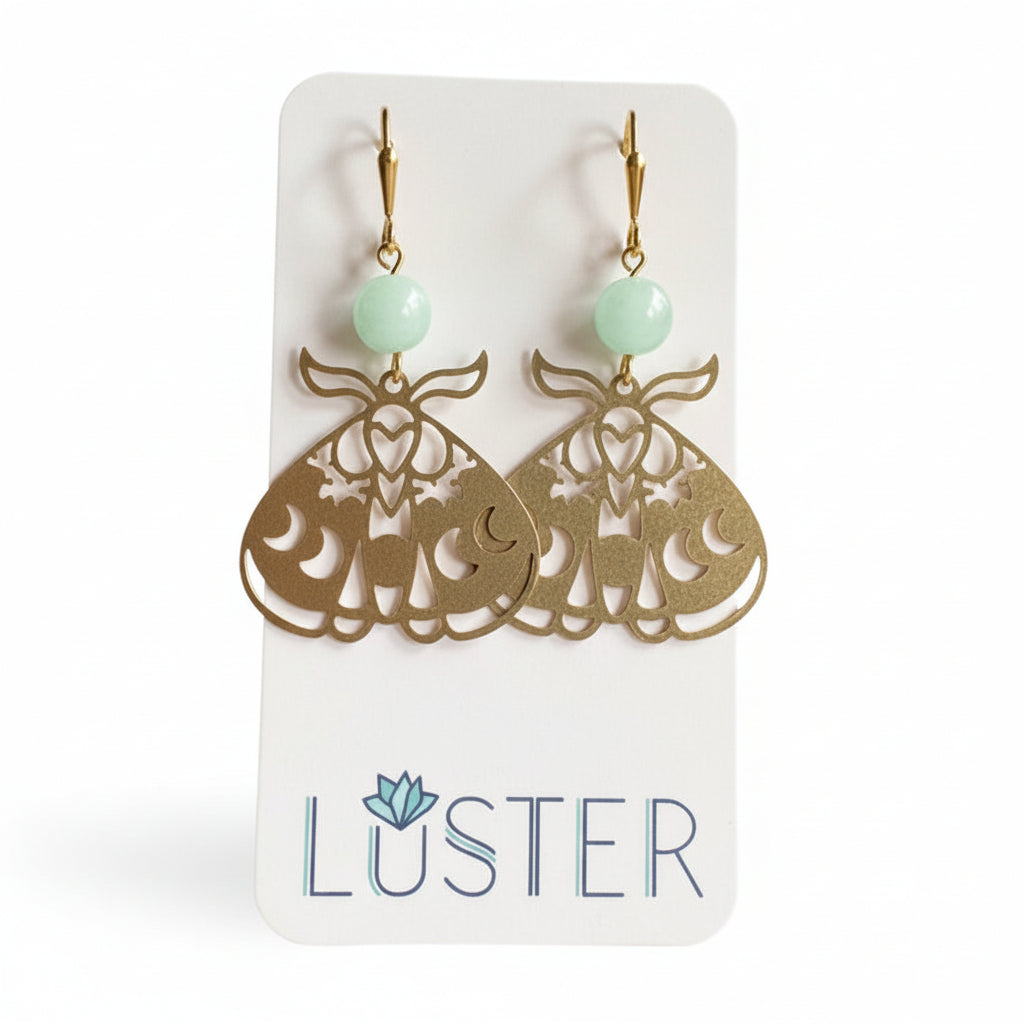 Gold earrings with green beads on a Luster branded card