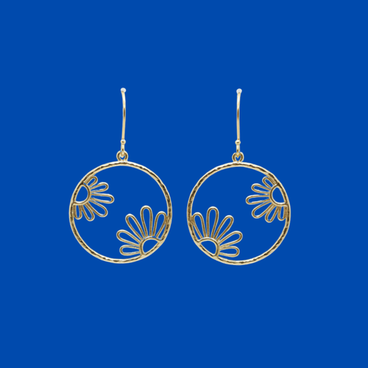 A pair of gold-tone dangle earrings with open circular hoops and floral fan motifs, shown against a solid blue background.