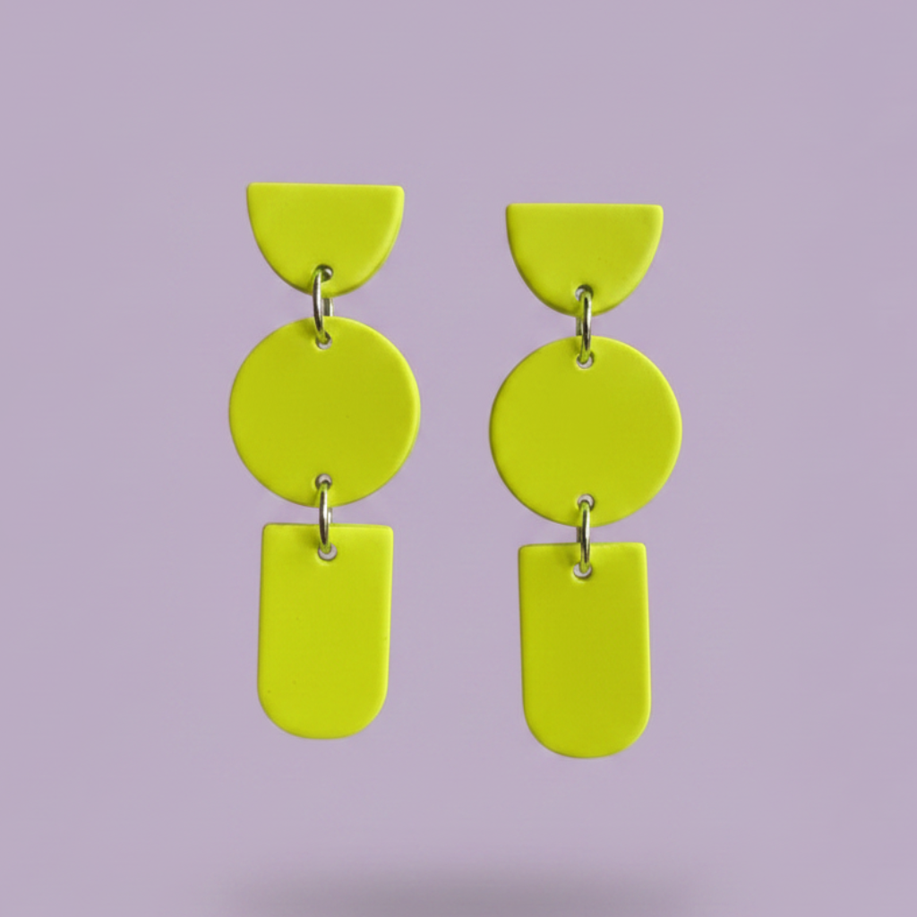 A pair of bright lime green geometric drop earrings with silver-tone metal rings, shown against a solid lavender background.