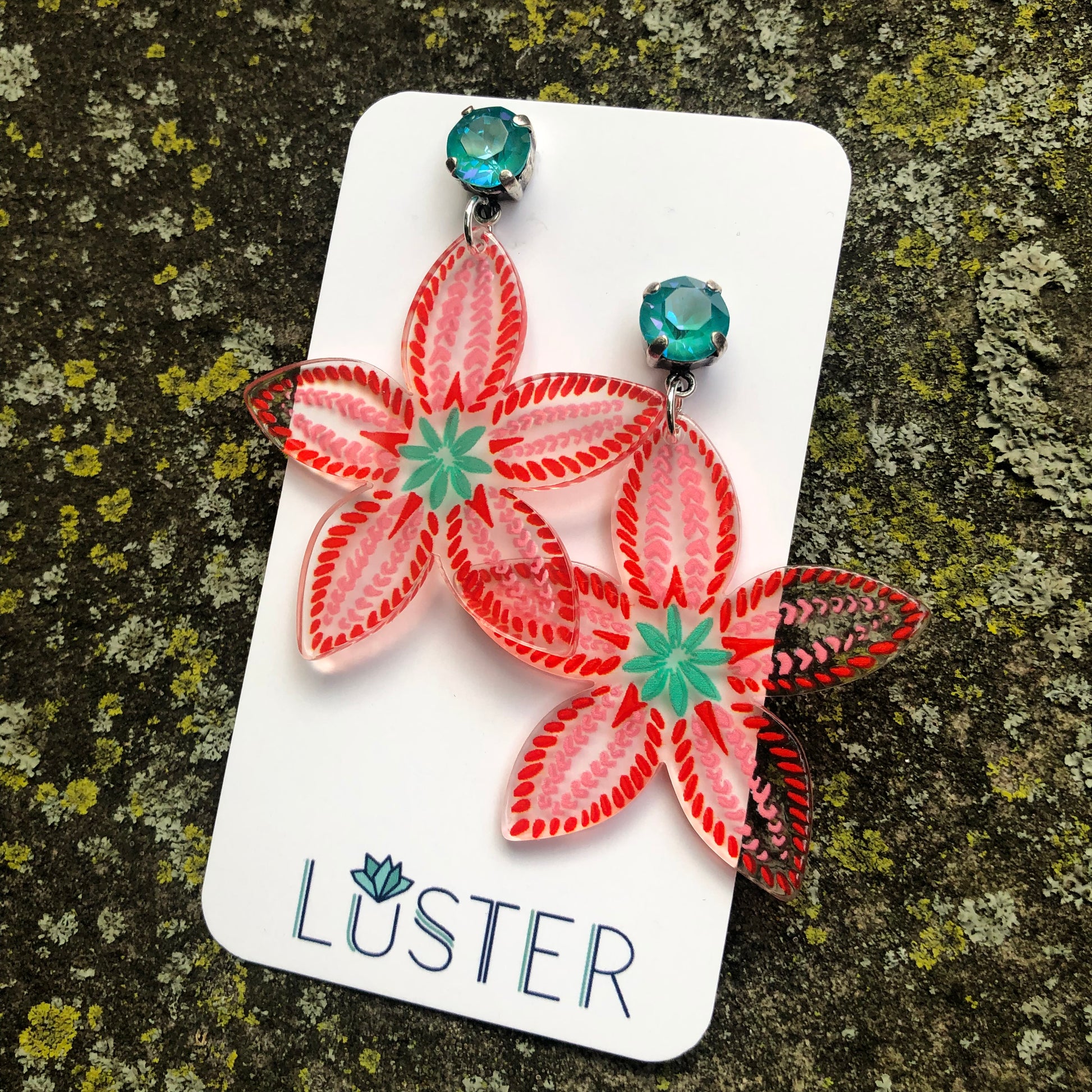 Floral earrings on a Luster branded card against a textured background