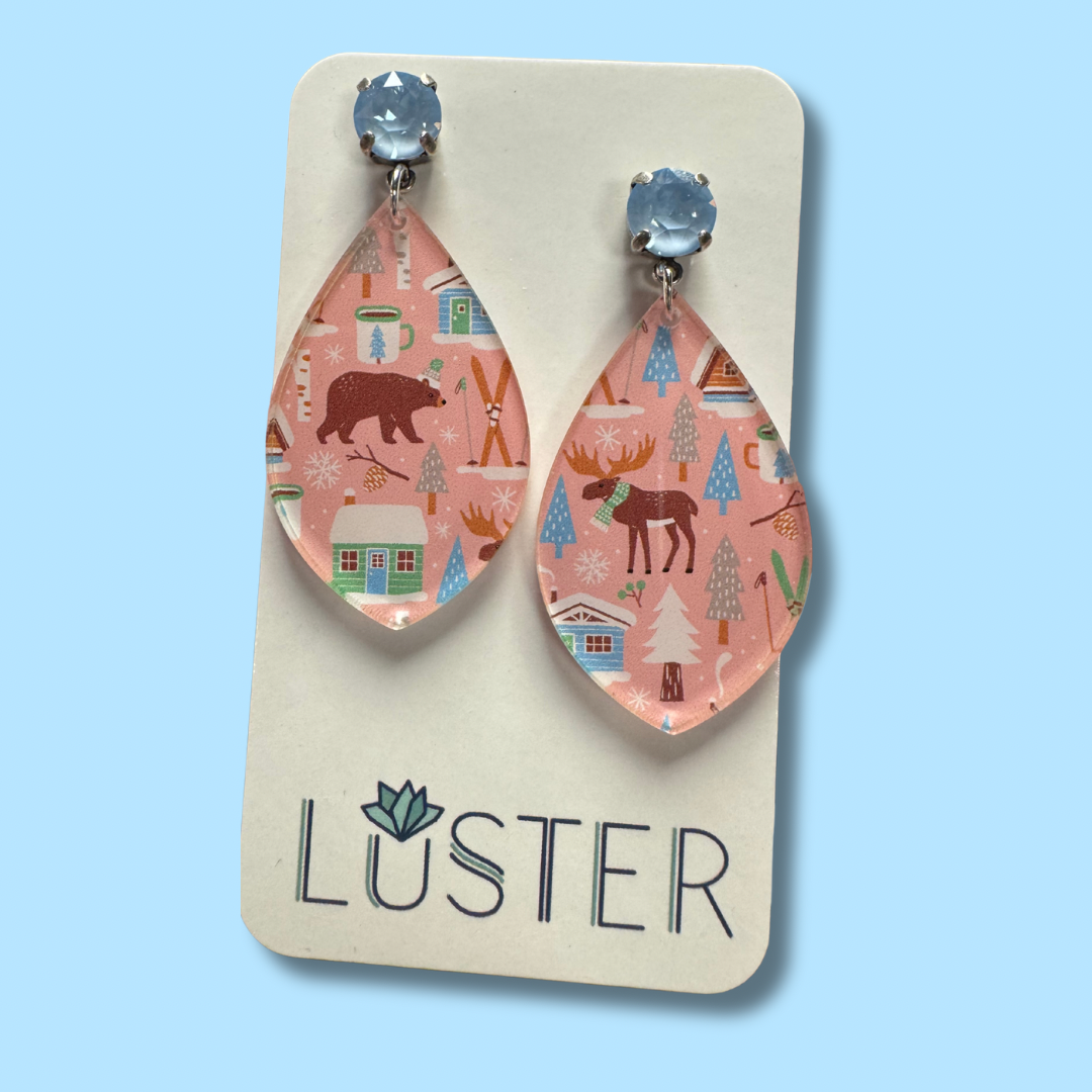 Teardrop-shaped earrings with nature-themed design on a 'Luster' branded card against a light blue background