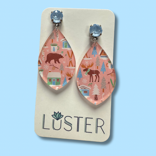 Teardrop-shaped earrings with nature-themed design on a 'Luster' branded card against a light blue background