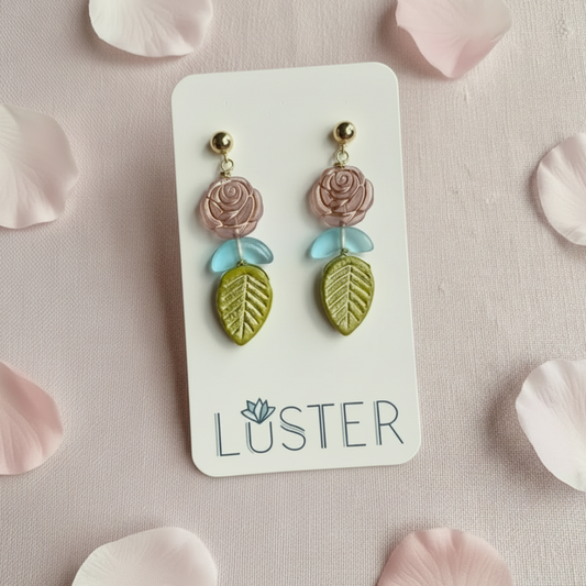 Pair of floral earrings on a Luster branded card with pink petals around