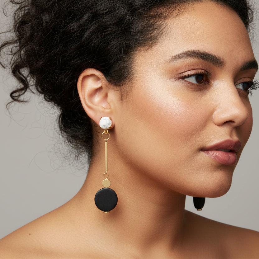 Pair of black and gold earrings on a Luster branded card on a model.