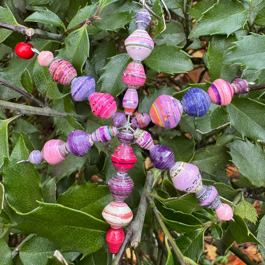 Colorful beaded ornament hanging on a branch with green leaves