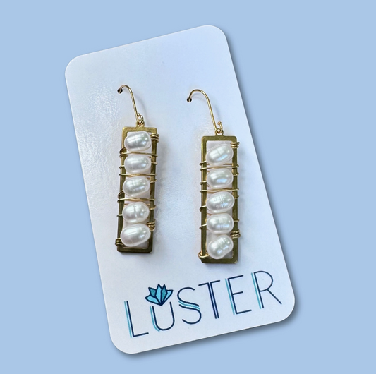 A pair of handwrapped pearl drop earrings displayed on a white card with the brand name 'LUSTER' written at the bottom.