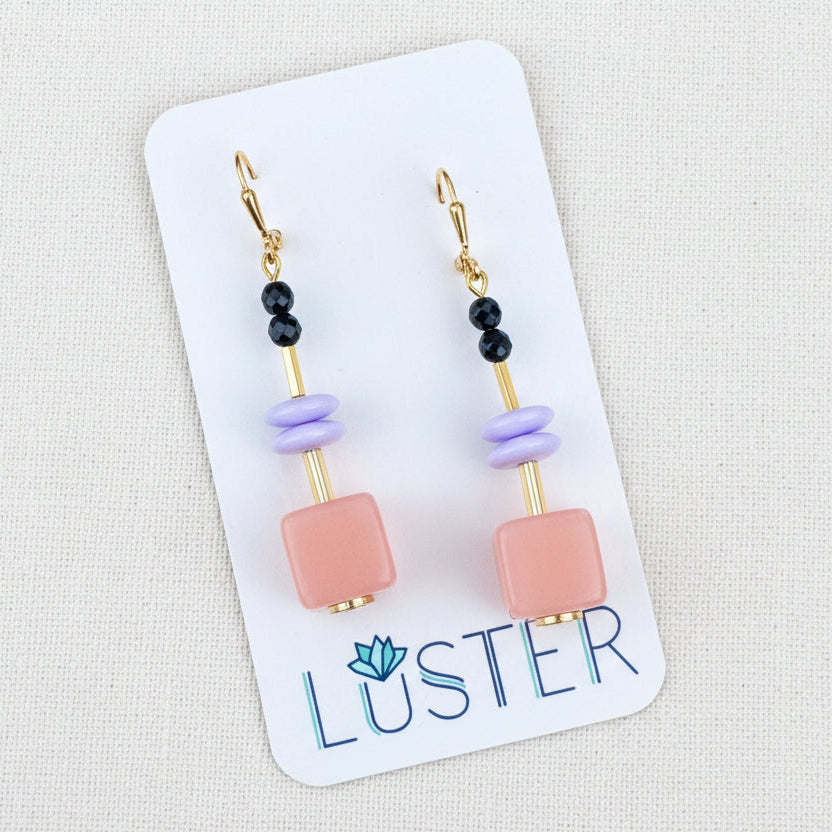 Pair of earrings on a Luster branded card against a textured background