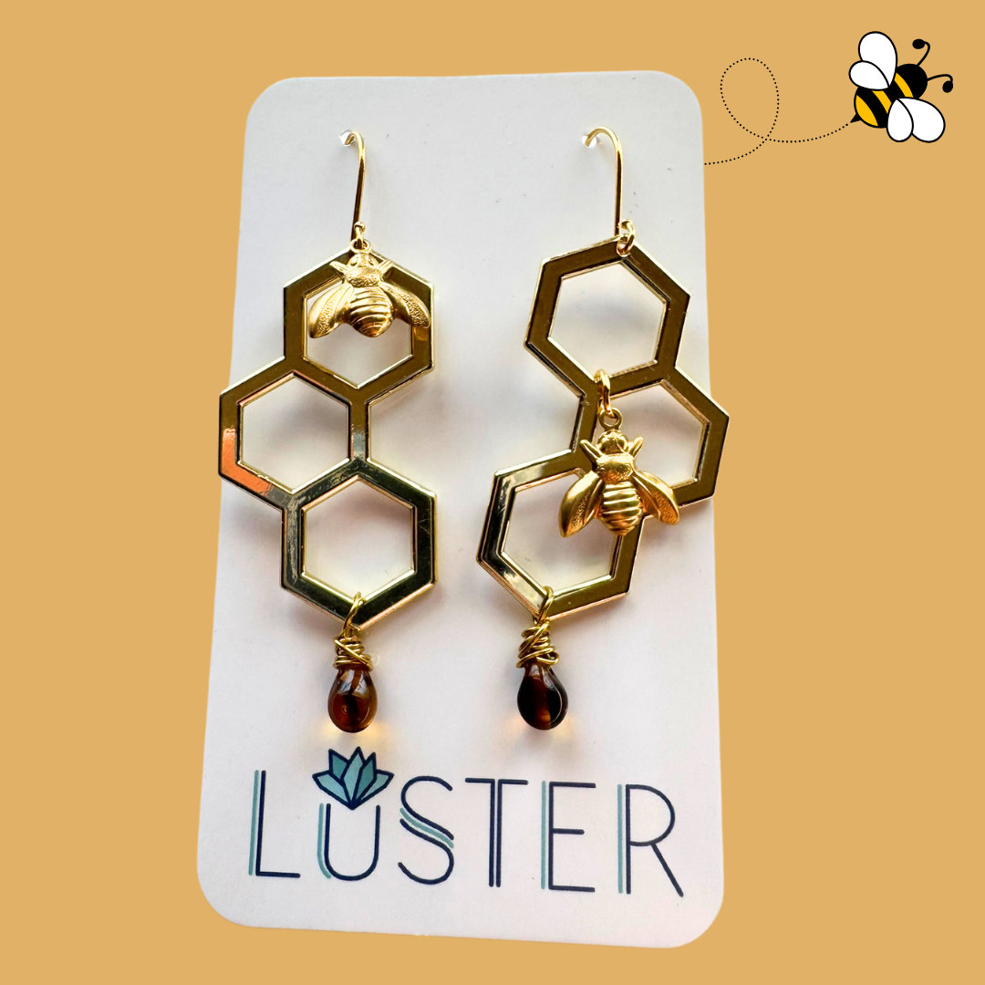 Gold bee and honeycomb earrings on a Luster branded card with a yellow background