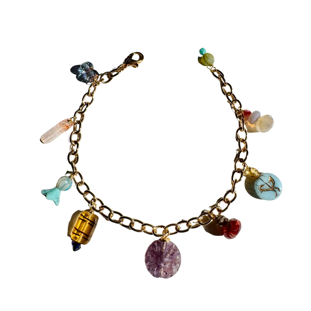 Gold bracelet with various charms on a white background