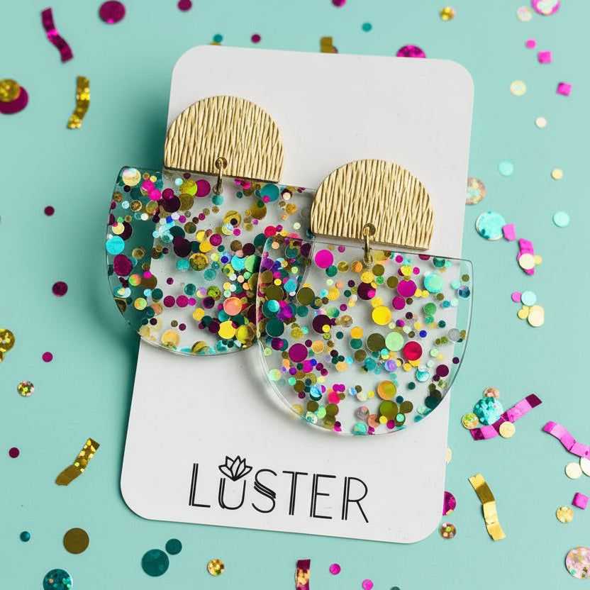 Colorful confetti earrings on a white card with 'Luster' branding.