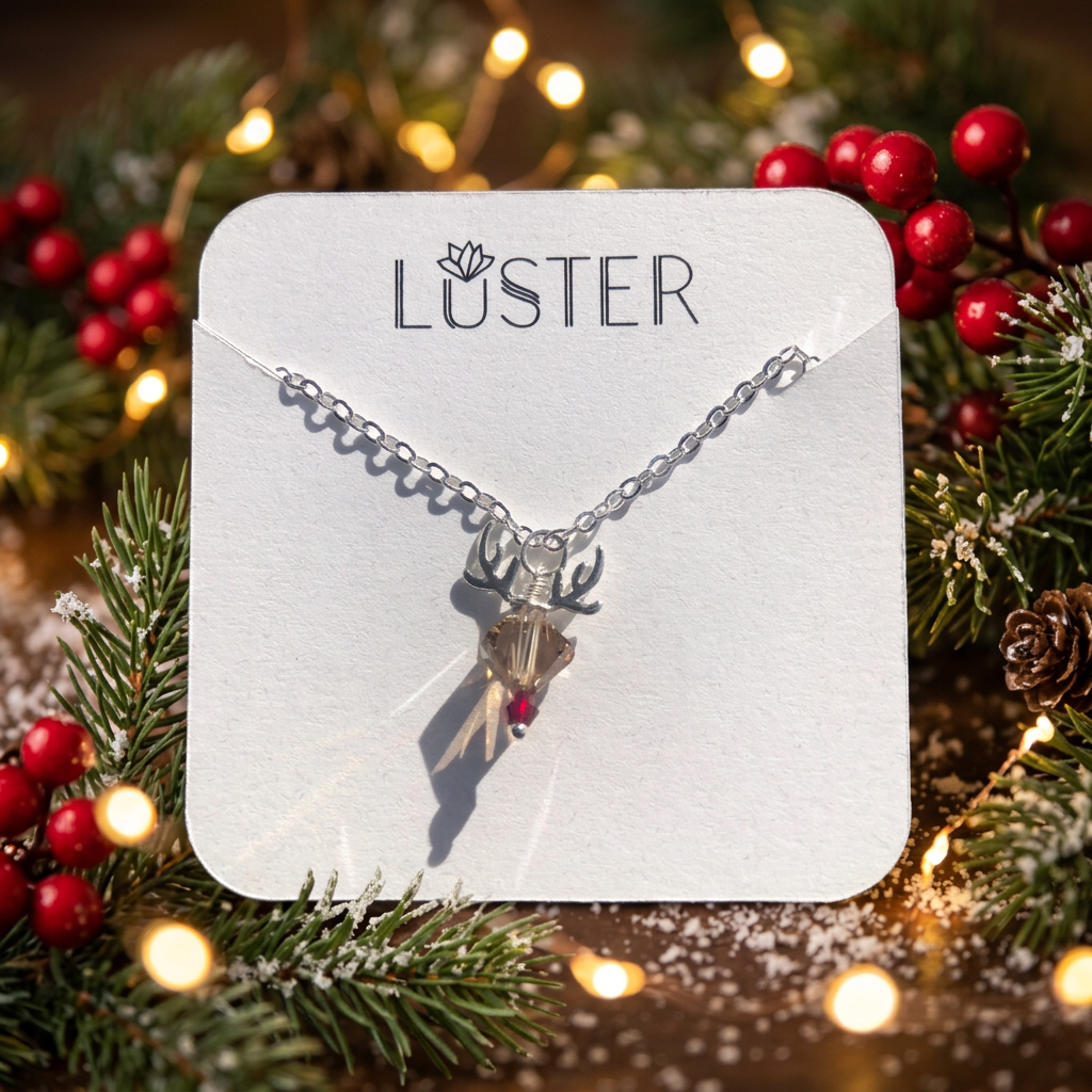 A reindeer crystal pendant on a silver chain displayed on a white branded card against a holiday scene.