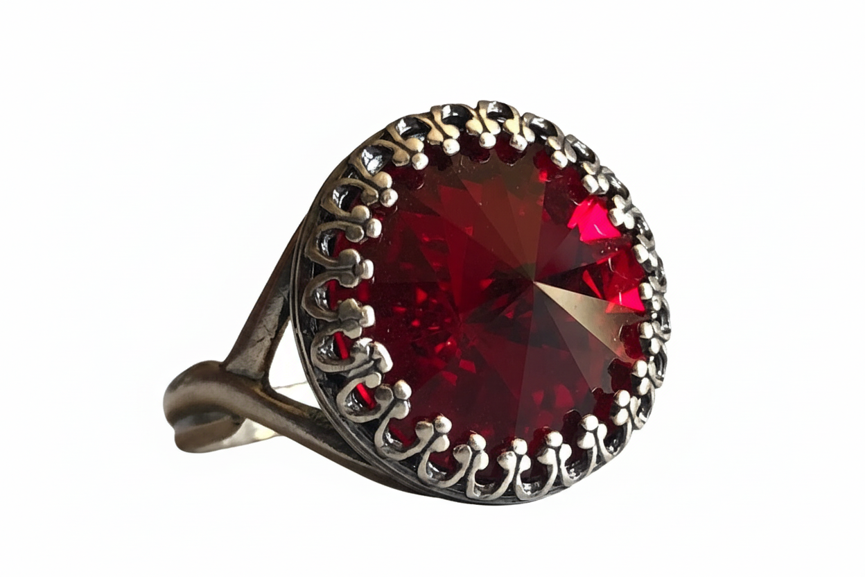 Ring with a large red gemstone and silver decorative band on a neutral background